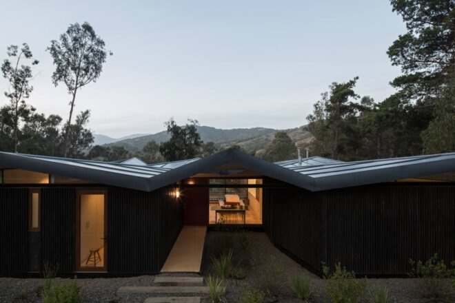 low-rise home with zigzag metal roof all lit up at night