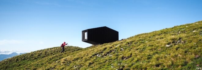 black mountain shelter high in mountains surrounded by greenery