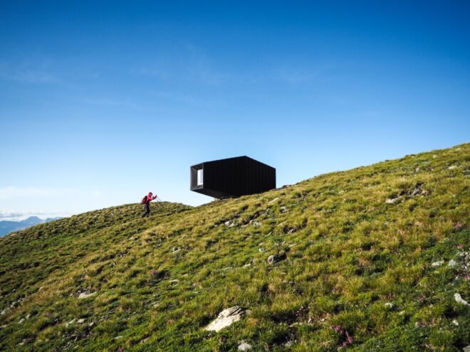 black mountain shelter high in mountains surrounded by greenery