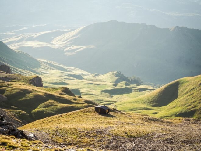 black mountain shelter high in mountains surrounded by greenery