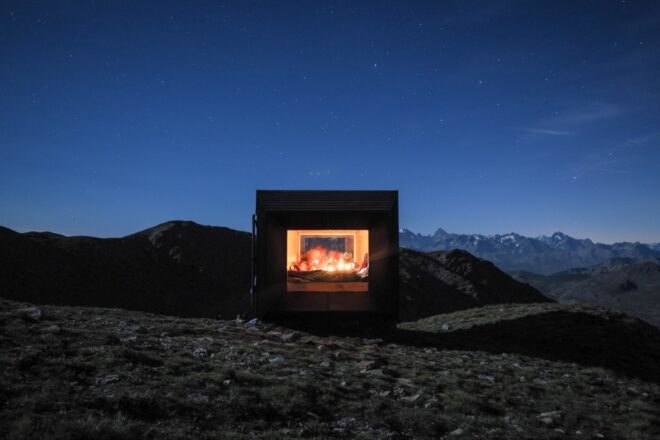 black mountain shelter high in mountains surrounded by greenery