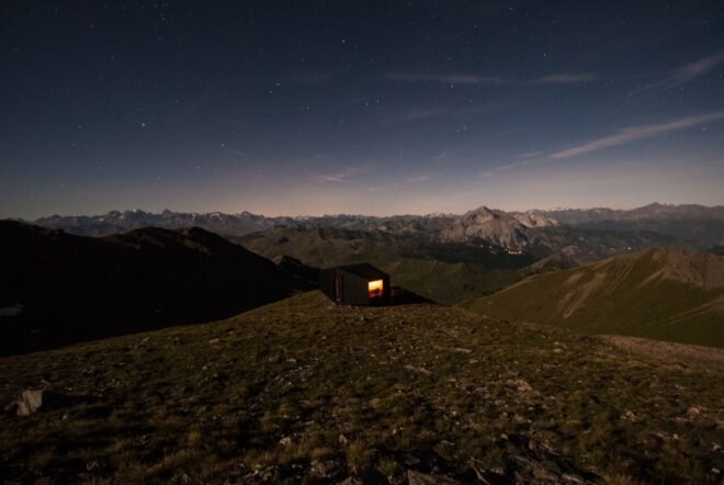 black mountain shelter high in mountains surrounded by greenery