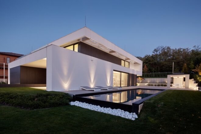 black and white home with pool lit up at night