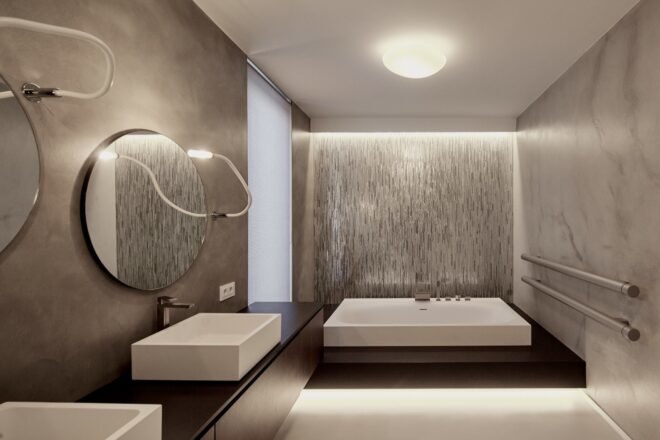 gray bathroom with white sinks, dark wood counters and recessed lighting
