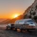 sun rising over mountains and reflecting off an aluminum travel trailer