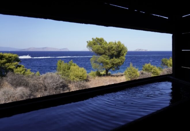 cut-out in a charred wood pavilion revealing views of water and trees