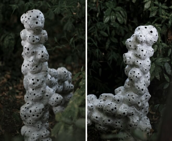 white sculptures with holes in a yard