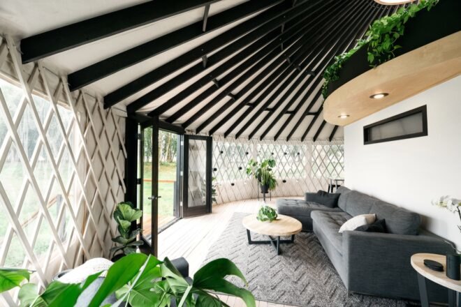 round interior with gray sofa and dark wood ceiling beams