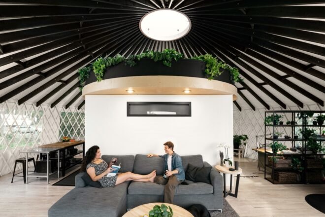 couple sitting on gray sofa in round room with a skylight