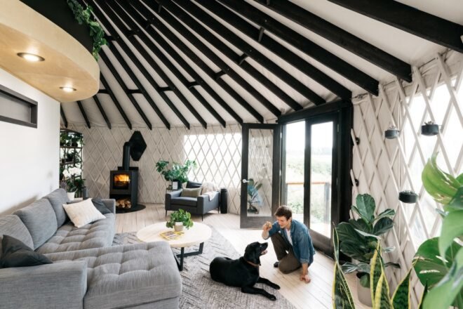 person talking to dog in a round room with gray sofa
