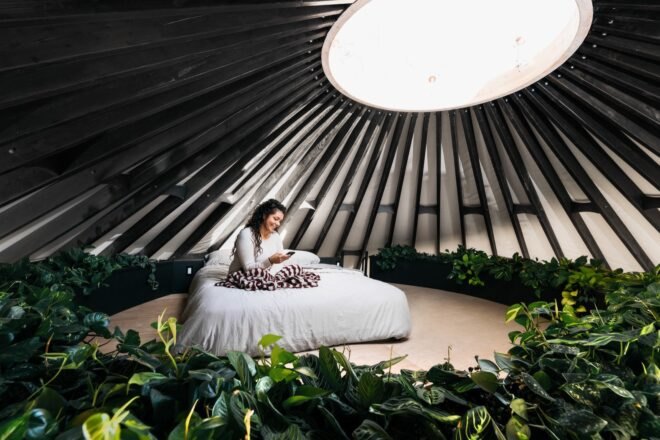 person sitting on bed in a loft under a round skylight