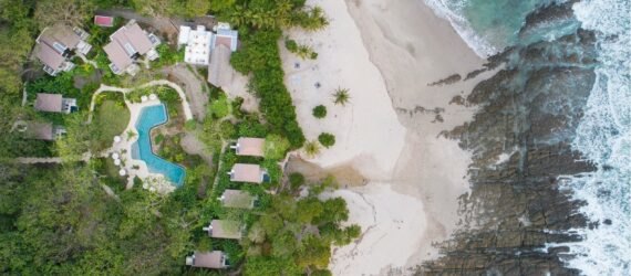 aerial shot of beachfront hotel bungalows and swimming pool
