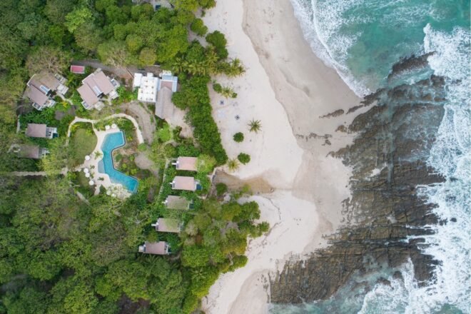 aerial shot of beachfront hotel bungalows and swimming pool