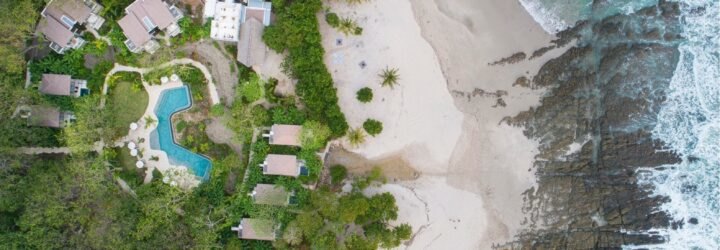 aerial shot of beachfront hotel bungalows and swimming pool
