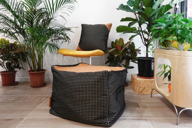 tan leather and black and white fabric pillow on a white chair in room filled with plants