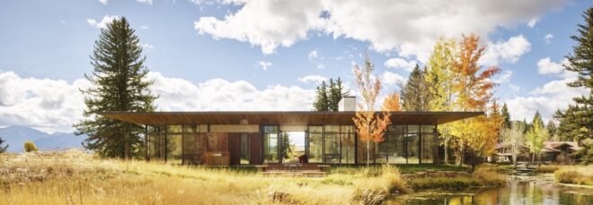 single story home with wooden facade surround by trees and waterways