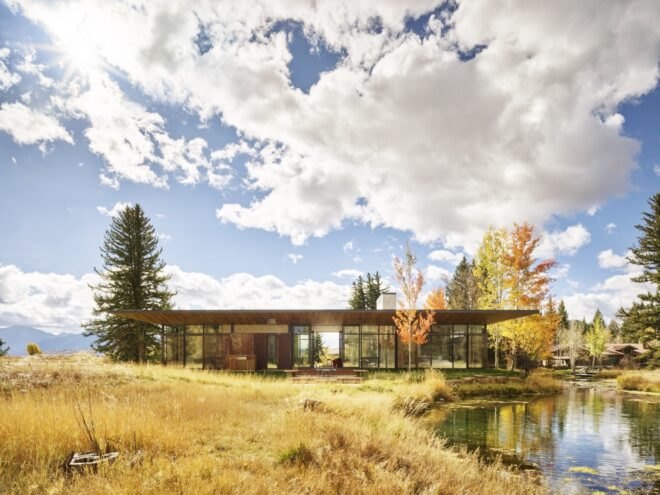 single story home with wooden facade surround by trees and waterways
