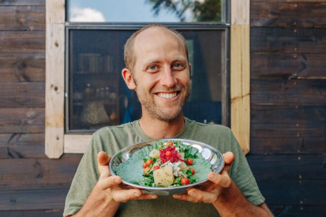 Rob Greenfield holding plate with collard green wrap