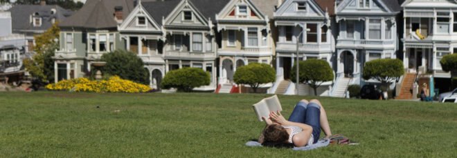 Person lying in grass reading a book in San Francisco