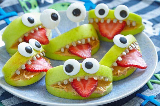 apples, strawberries and sunflower seeds arranged into a monster face