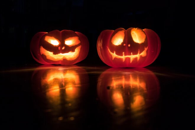 two lit-up Jack-o'-Lanterns in a dark room