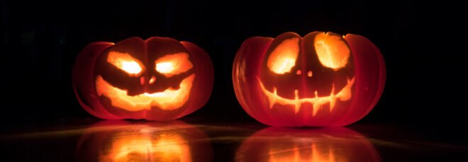 two lit-up Jack-o'-Lanterns in a dark room