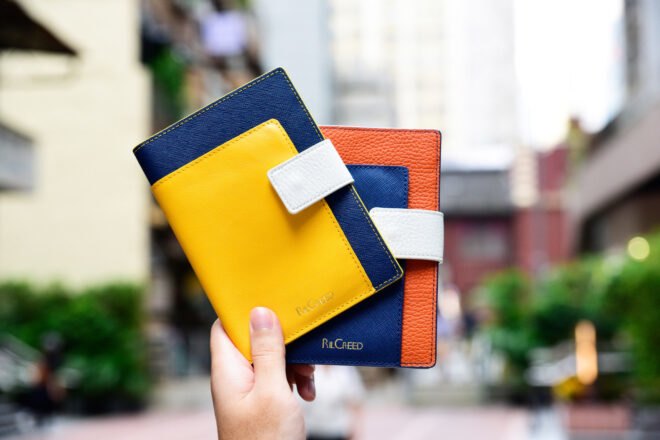 person holding colorful leather passport holders