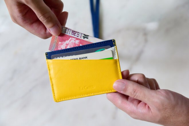 person pulling money out of yellow card holder