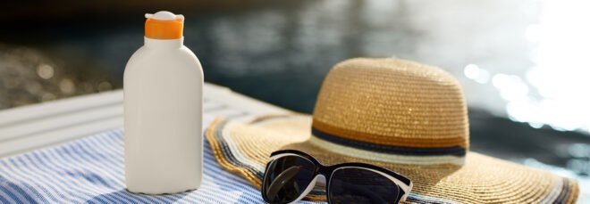 sunscreen, glasses and a hat by water