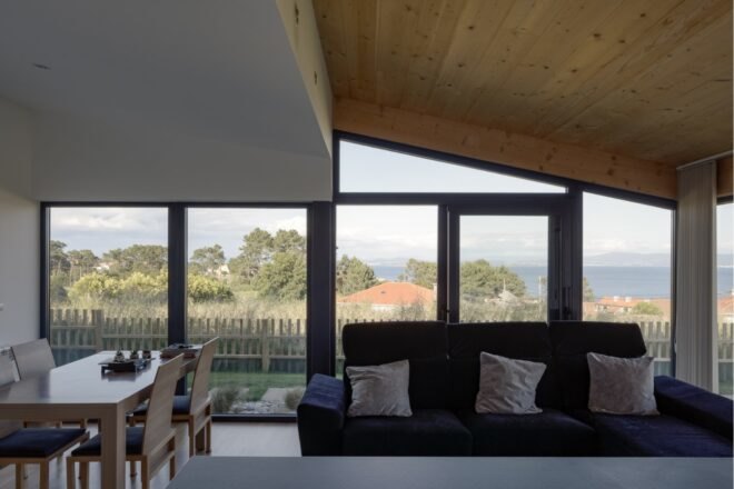 dark sofa and open kitchen in home with glass walls
