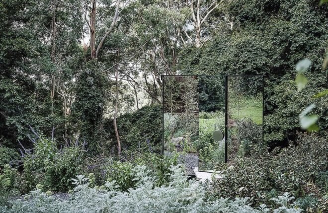 small mirrored building in a forest