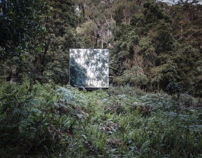 end of a small mirrored building in a forest