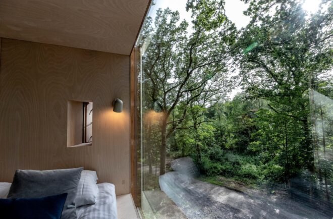 bed beside glass wall with forest views