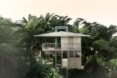 a multi-level house built on stilts and surrounded by palm trees