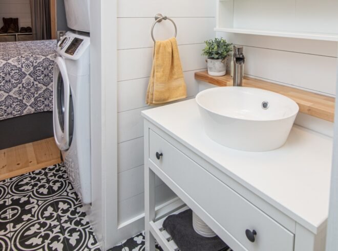 black, white and light wood bathroom with washer and dryer