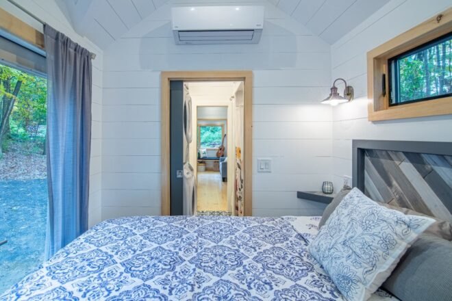 gray and white bedroom with door open to a hallway inside a tiny home