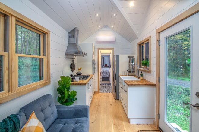 white tiny home interior with gray sofa and white and light wood kitchen