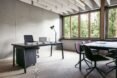 black desks in a room with several windows revealing views of trees