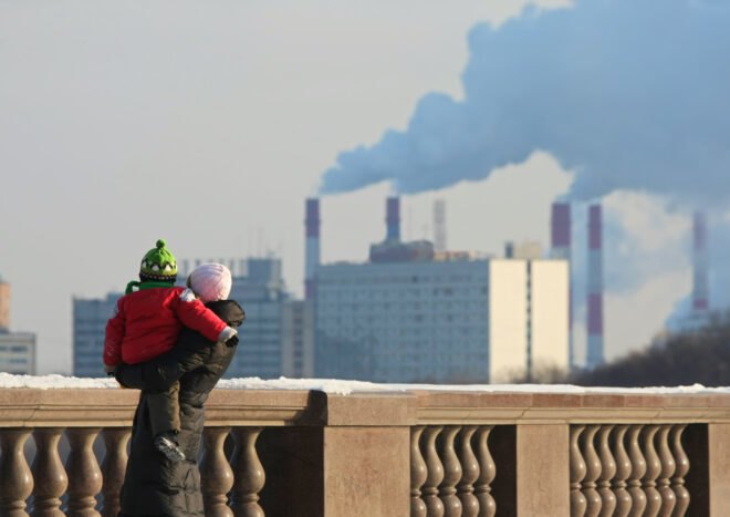 Woman with the child looking out at pipes with a smoke
