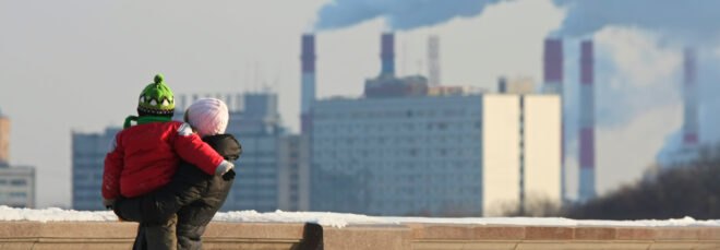 Woman with the child looking out at pipes with a smoke