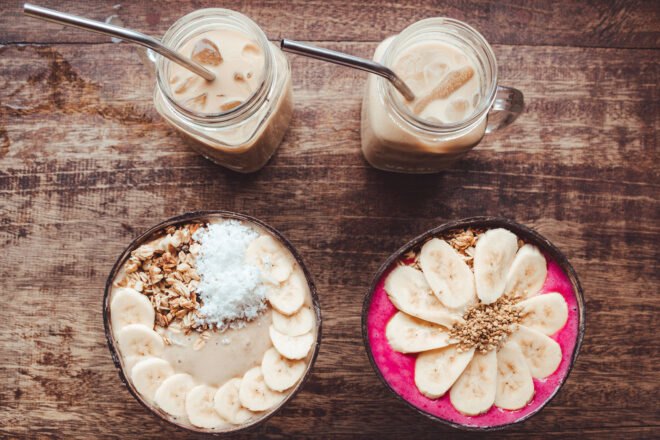 smoothie bowls next to glasses of coffee with steel straws