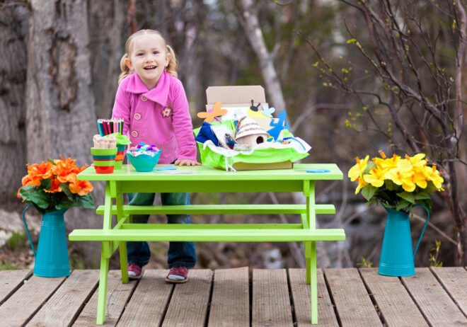 child playing with science craft kit outside at green picnic table