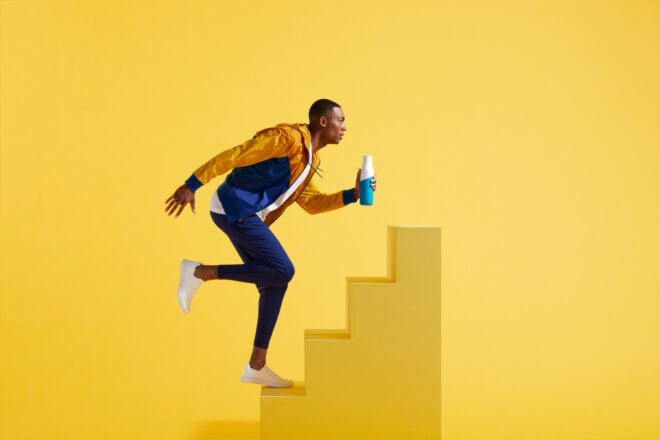 person holding water bottle and running up steps
