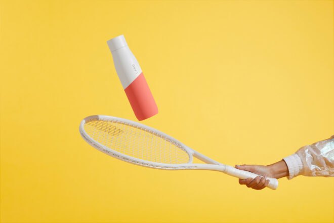 person hitting white and coral water bottle with a white tennis racket