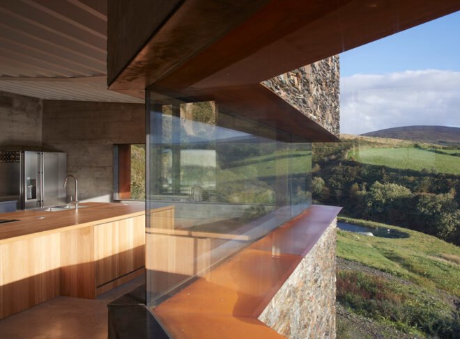 side view of stone home with long, narrow glass panel in the living area