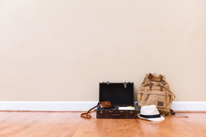 suitcase, backpack and hat neatly packed and sat next to a wall