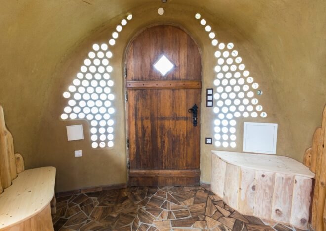 wood door surrounded by glass jars embedded in clay walls