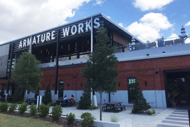 A tiered building with an Amarture Works sign and small green space in front of the building