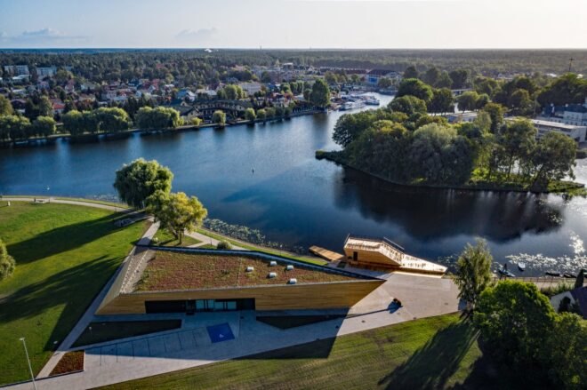 timber, green-roofed building near water