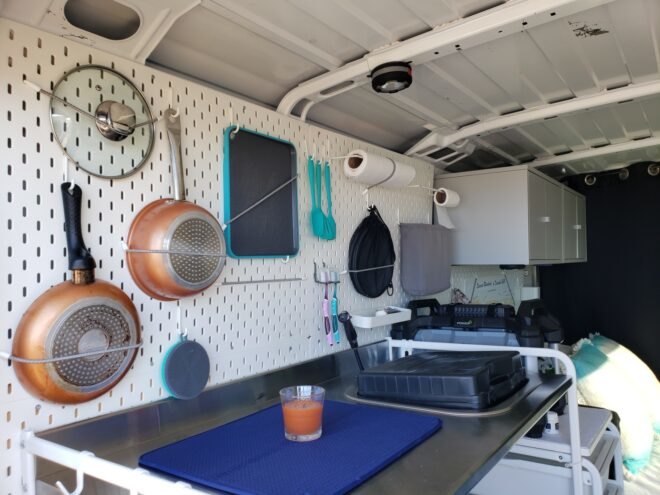 interior space of converted van, a small cooking area with pans hung up on the wall
